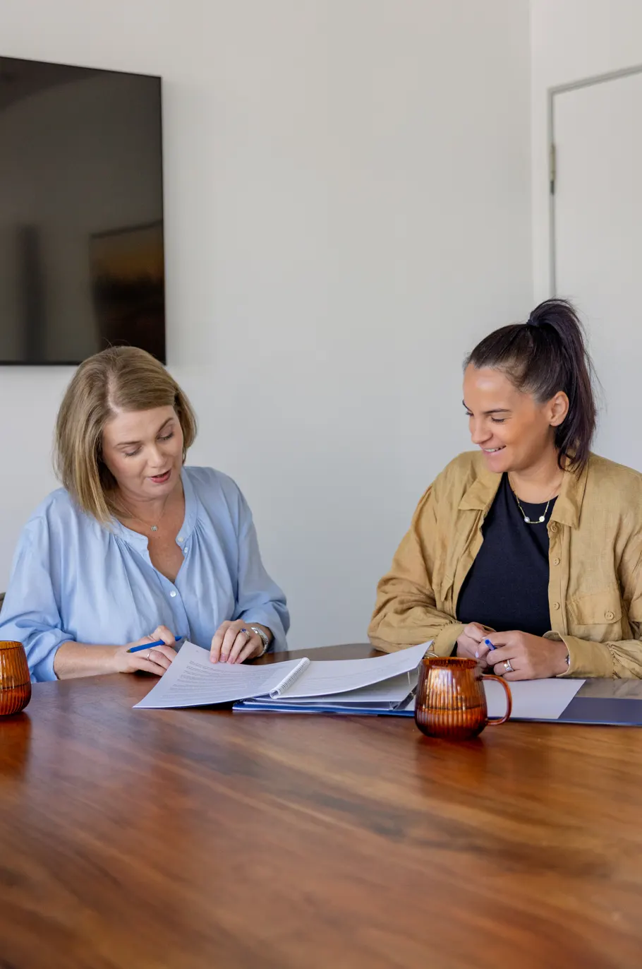 Two Wakefield Pacific team members working through financial paperwork at a boardroom table