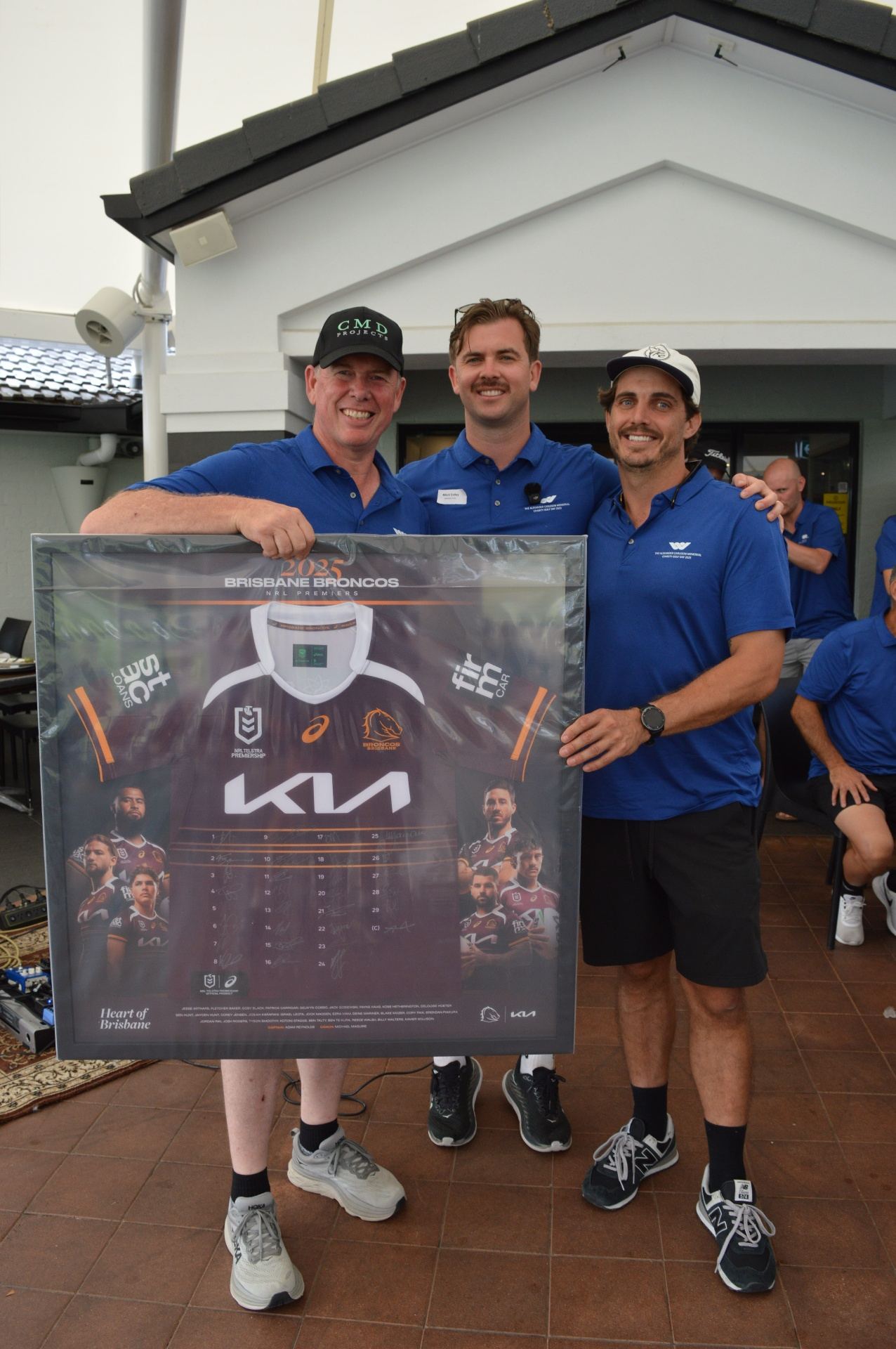 Mitch Calley with auction winners holding a signed Brisbane Broncos jersey