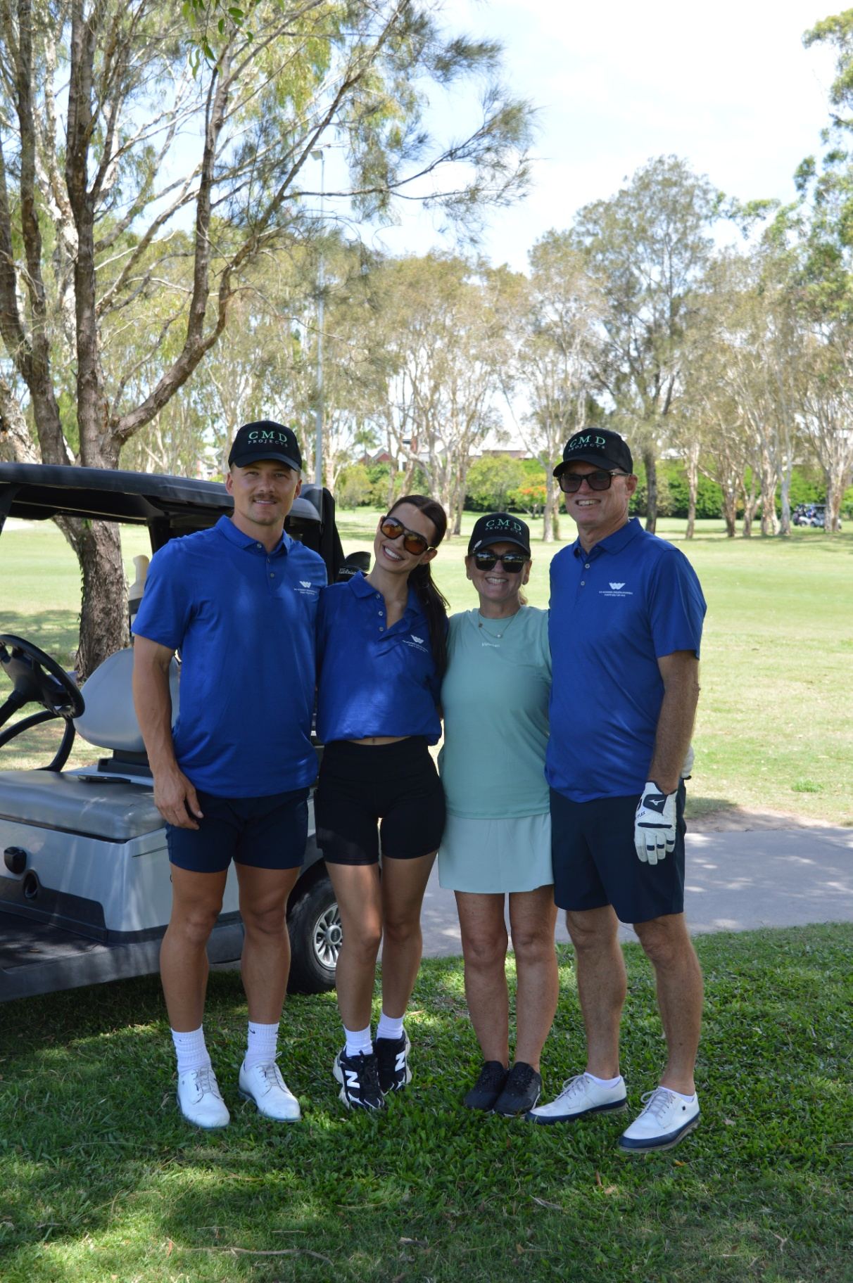 A foursome posing beside their cart on the course